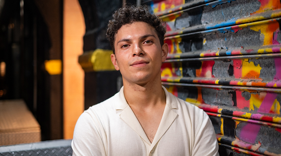 Guitarist Diego Retana pictured in front of a graffitied wall.