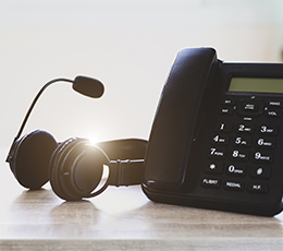 An office desk setup featuring a telephone and headset, symbolizing IT help desk support and telecommunication services for faculty and staff.